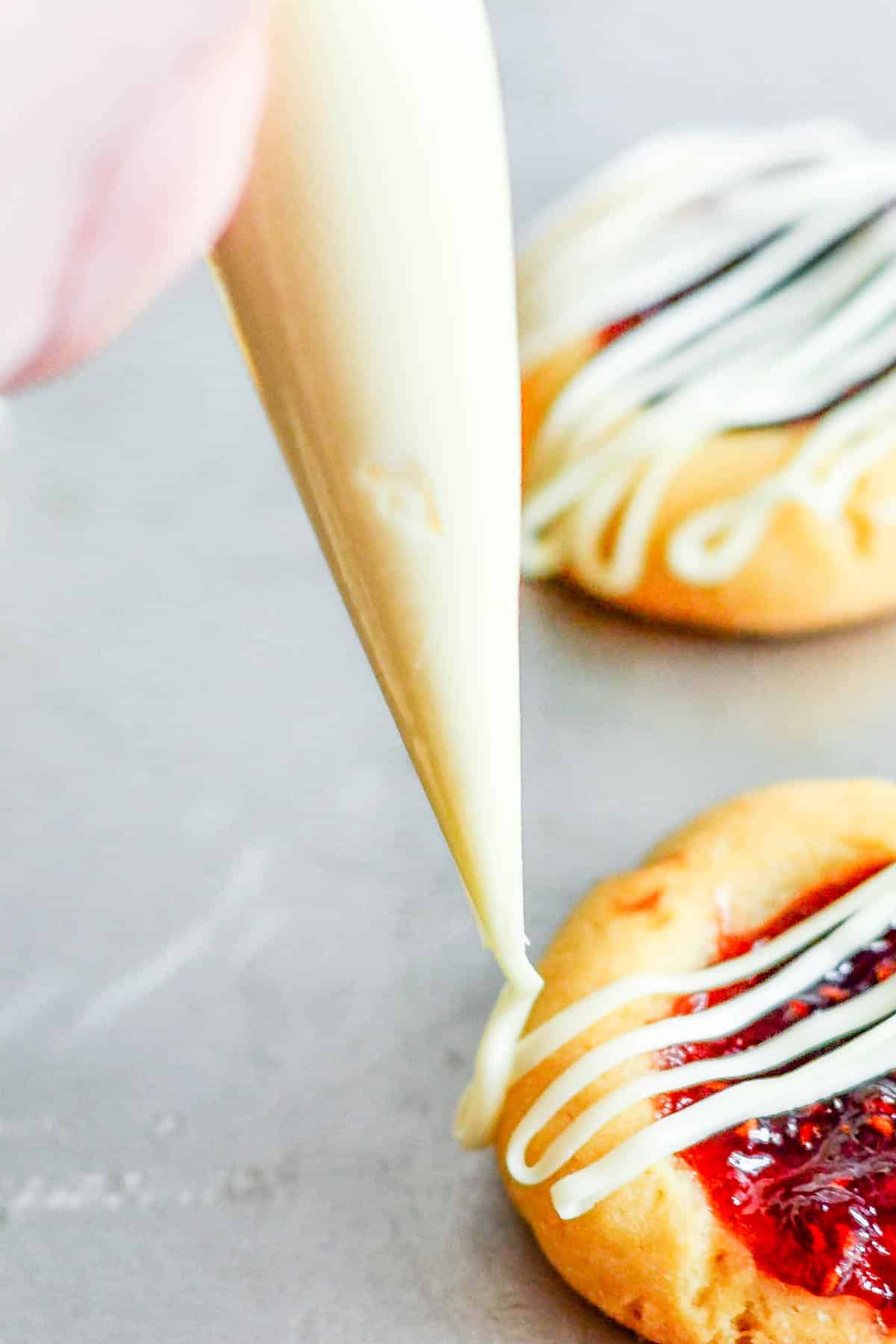 Drizzling white chocolate frosting on cookies.