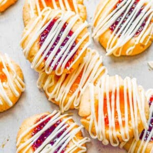 Jam filled thumbprint cookies on a baking sheet.