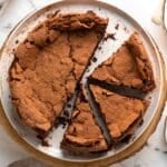 Chocolate cake on a cake plate, cut into pieces.