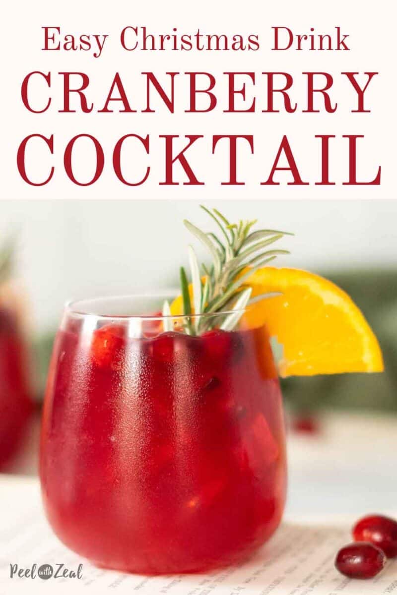 Cocktail glass with an orange slice, fresh cranberries, and a rosemary sprig garnish.