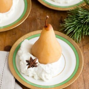 Poached pear on a plate with whipped cream and star anise.