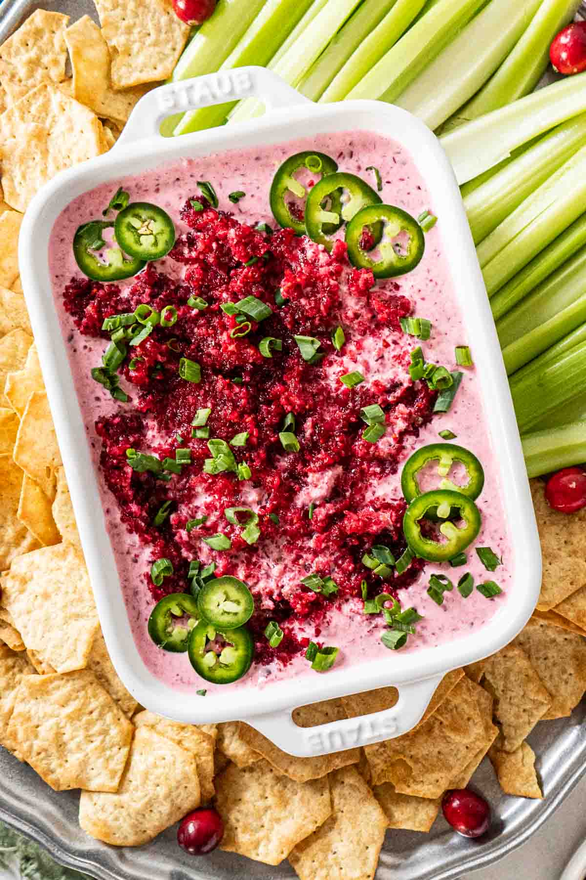 Cranberry cream cheese dip with jalapenos in a serving dish with crackers and celery.