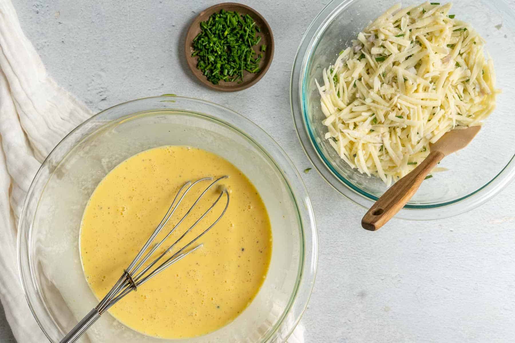 Ingredients for potato pancakes: beaten eggs whisked to perfection, shredded potatoes mingling with chopped chives on a light surface; consider adding flair by pairing with a slice of zucchini crustless quiche for a delightful brunch.