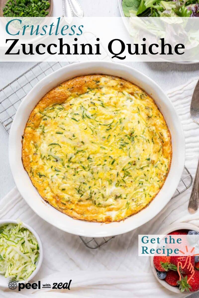 Zucchini crustless quiche graces a white dish, encircled by a vibrant salad, freshly shredded zucchini, and a scattering of berries on the table.