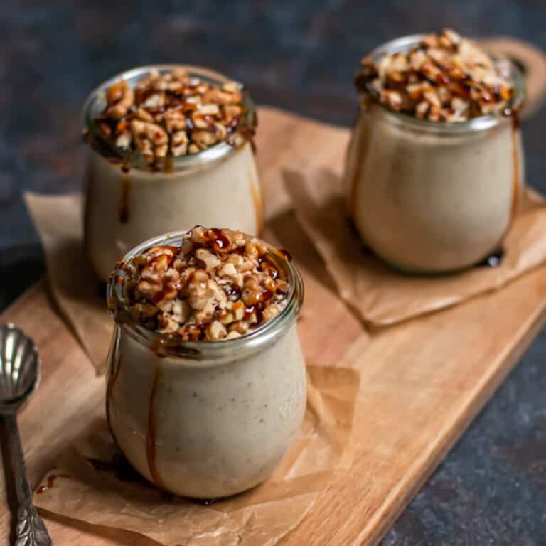Jars of fig pudding with walnuts an dsyrup on top.