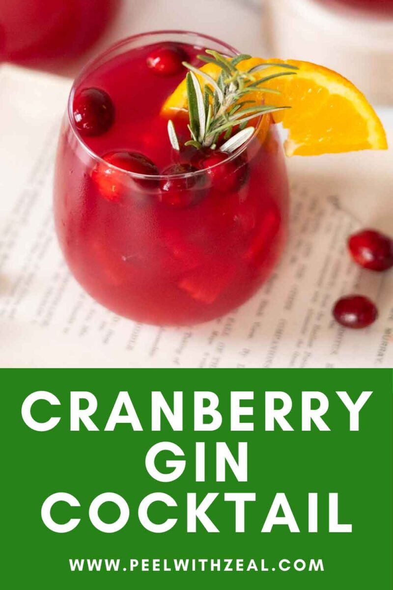 Cocktail glass with an orange slice, fresh cranberries, and a rosemary sprig garnish.