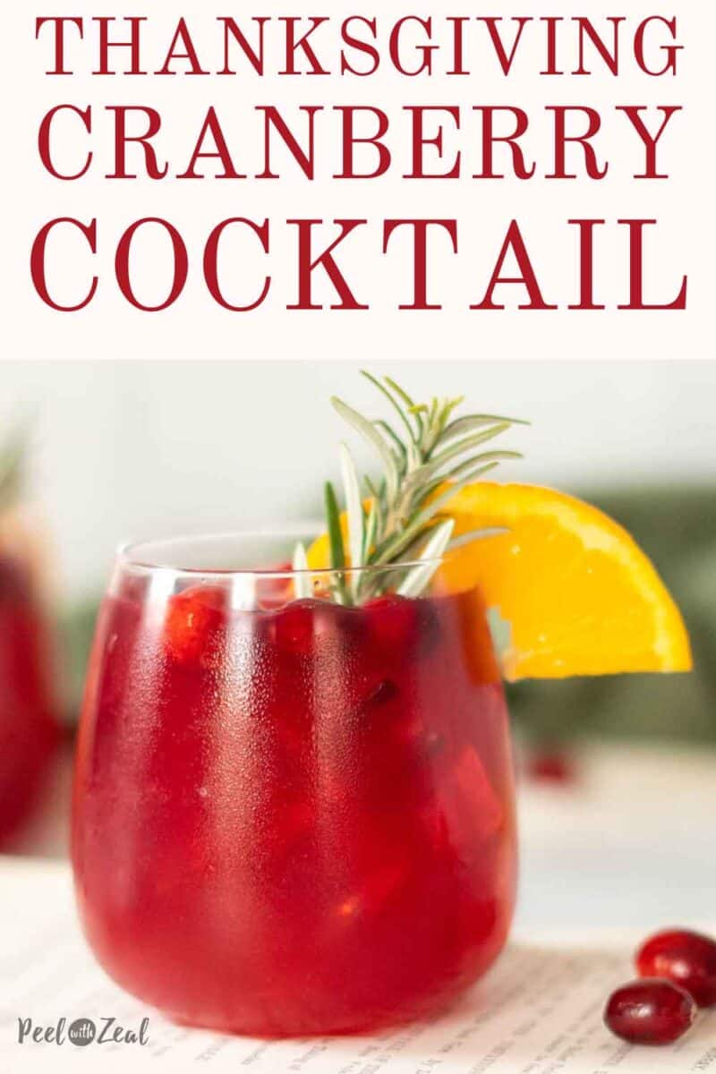 Cocktail glass with an orange slice, fresh cranberries, and a rosemary sprig garnish.