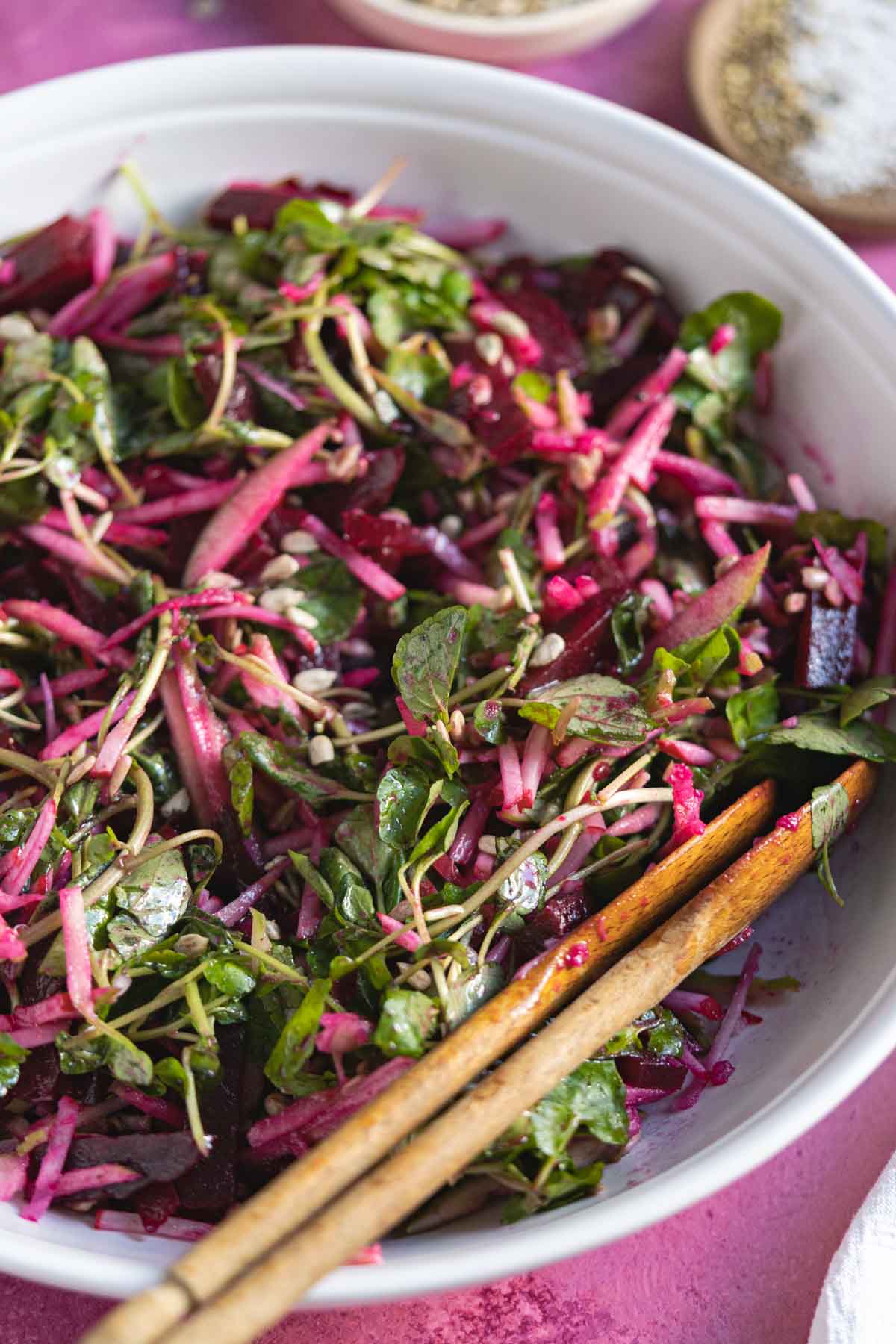 Watercress and beet salad with apples in a white bowl.