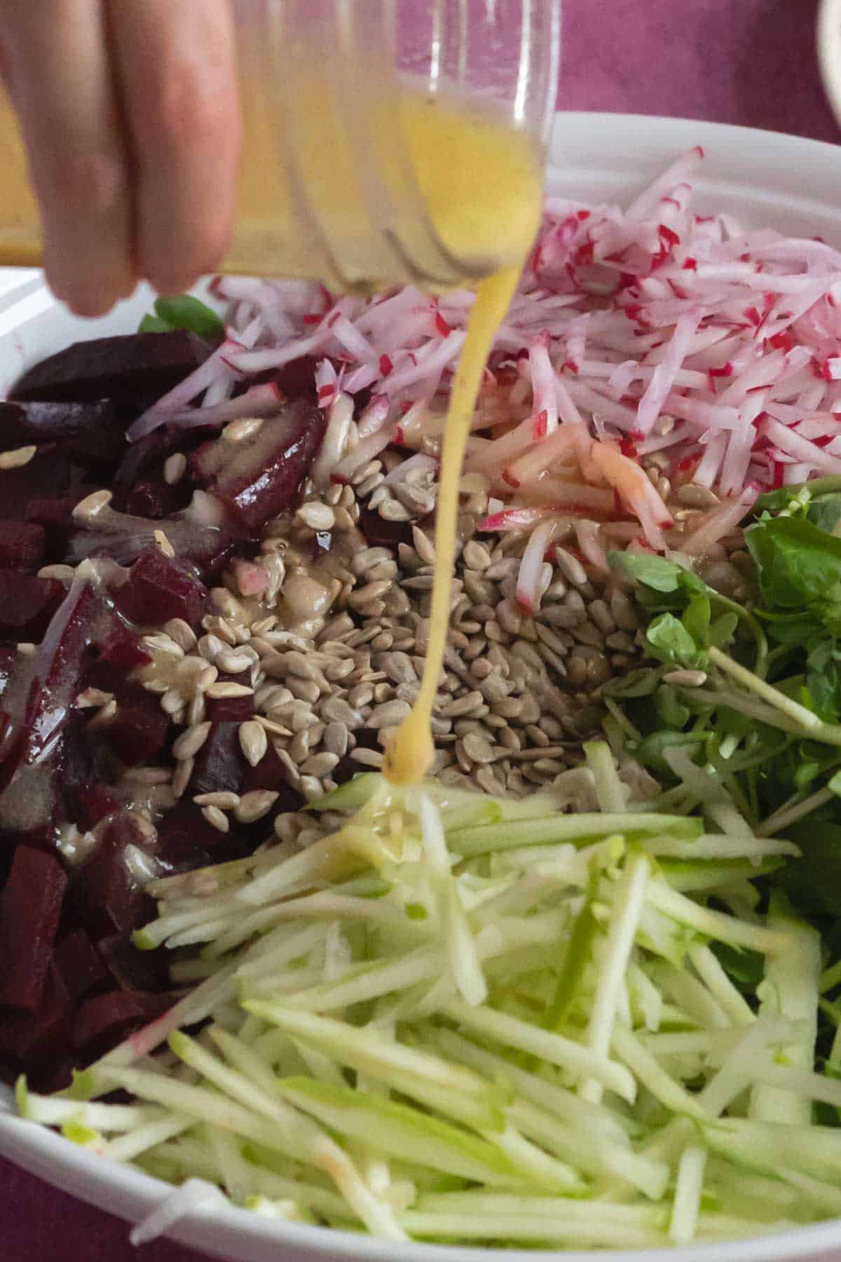 Person pouring dressing on a beet salad.