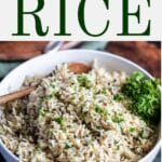 Rice with green herbs in a serving bowl with a wooden spoon.