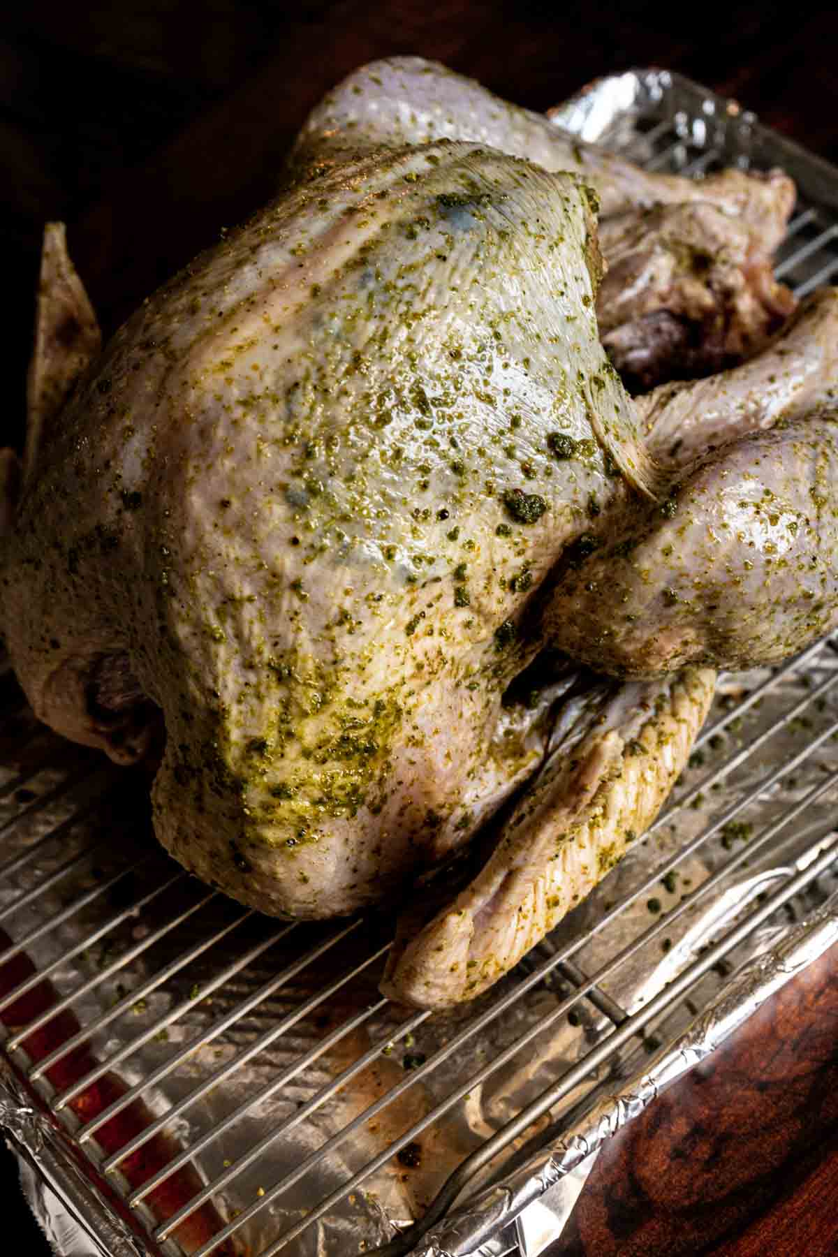 Raw whole turkey coated with dry brine on a wire rack over a foil-lined baking tray, showing how to dry brine a turkey for juicy, flavorful results.