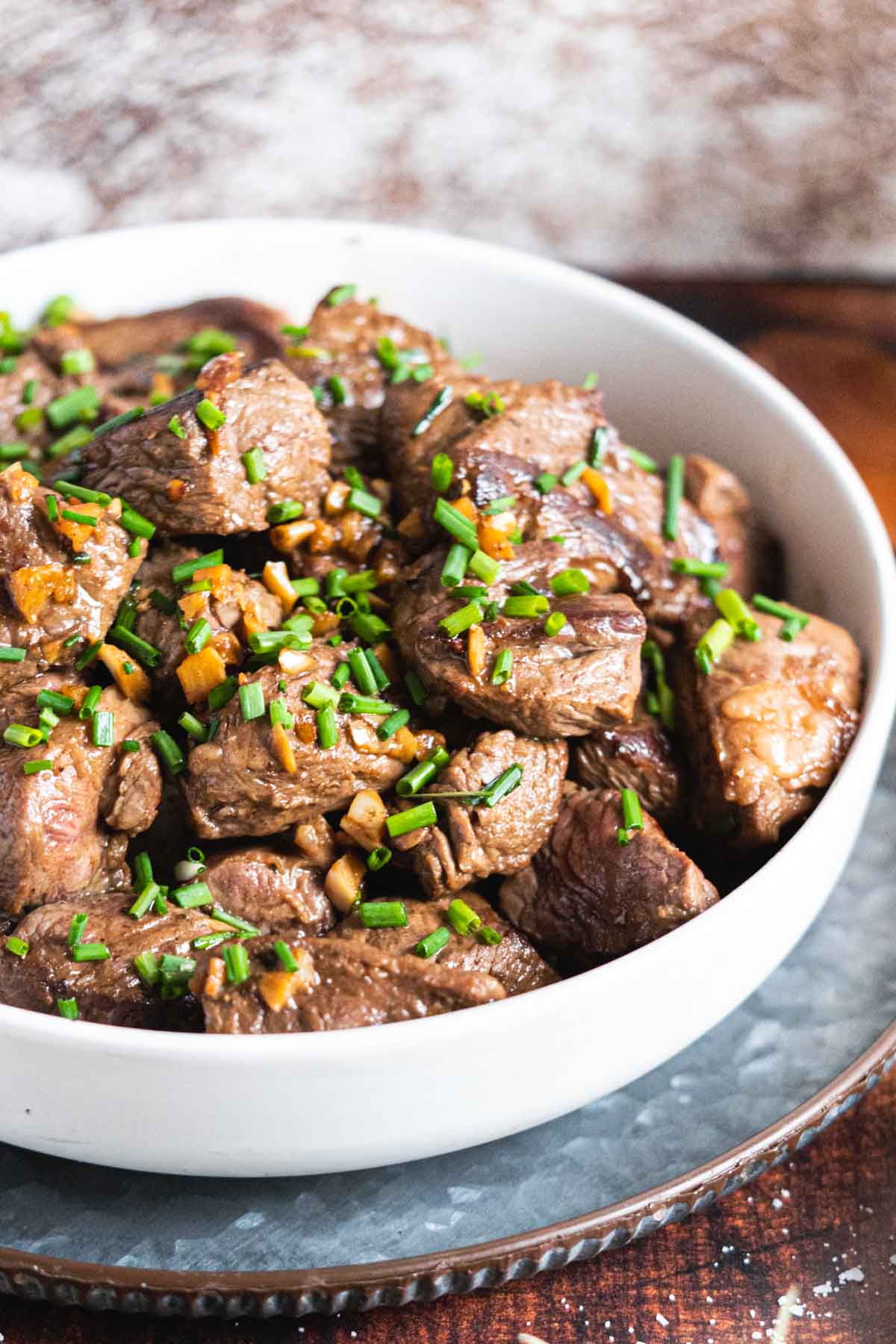 Steak bites with garlic and chives in a serving bowl.