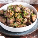 Steak bites with garlic and chives in a serving bowl.