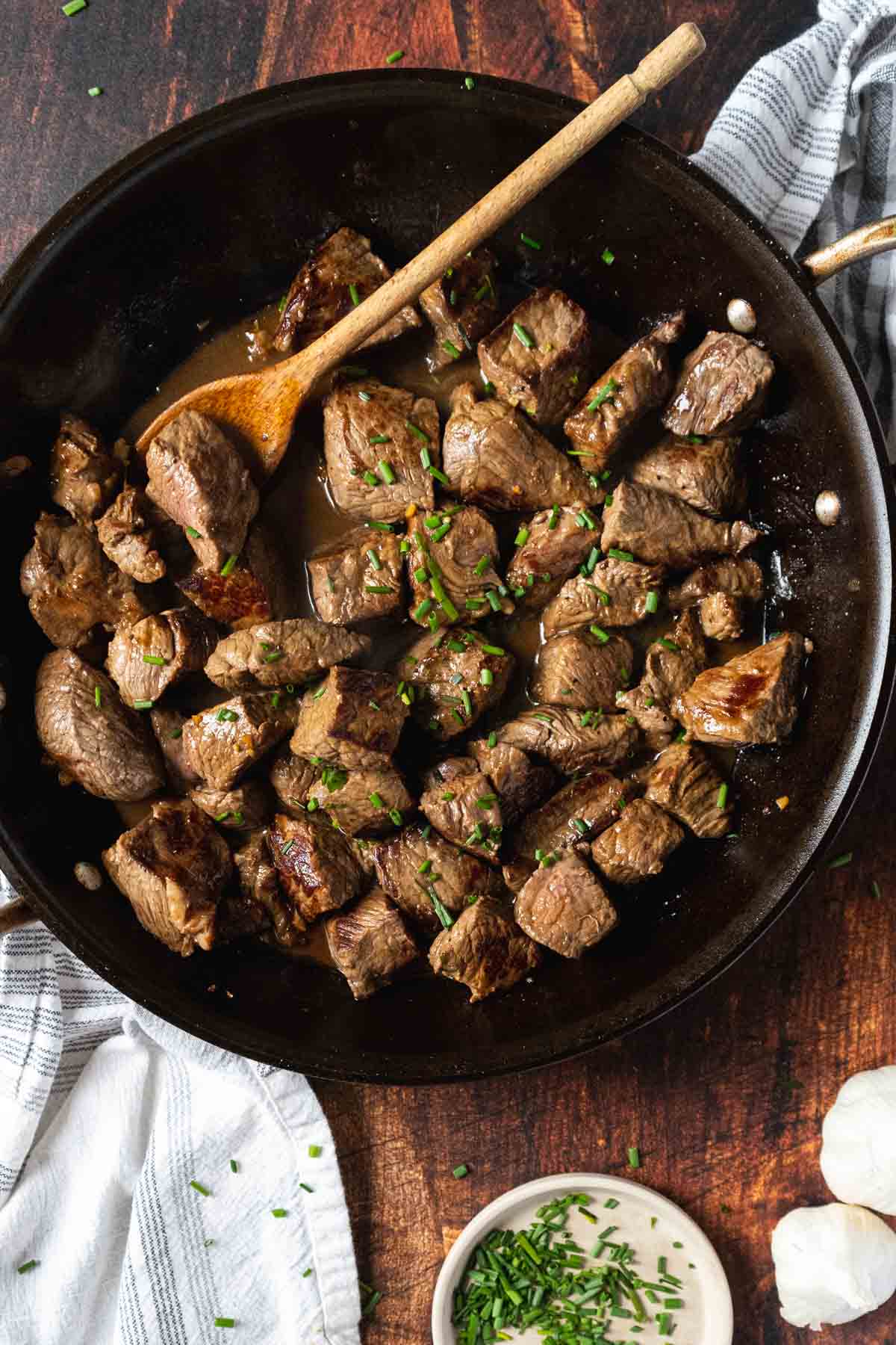 Steak bites with garlic sauce in a skillet.