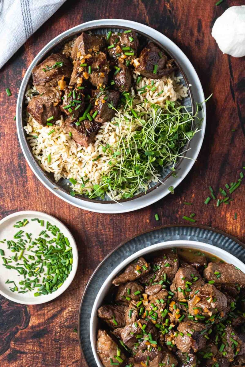 Steak bites served over rice with a salad.