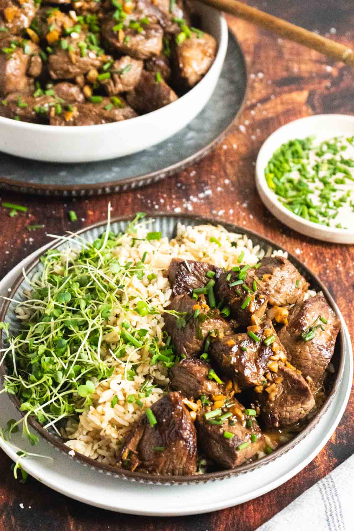 Steak bites served over rice with a salad.