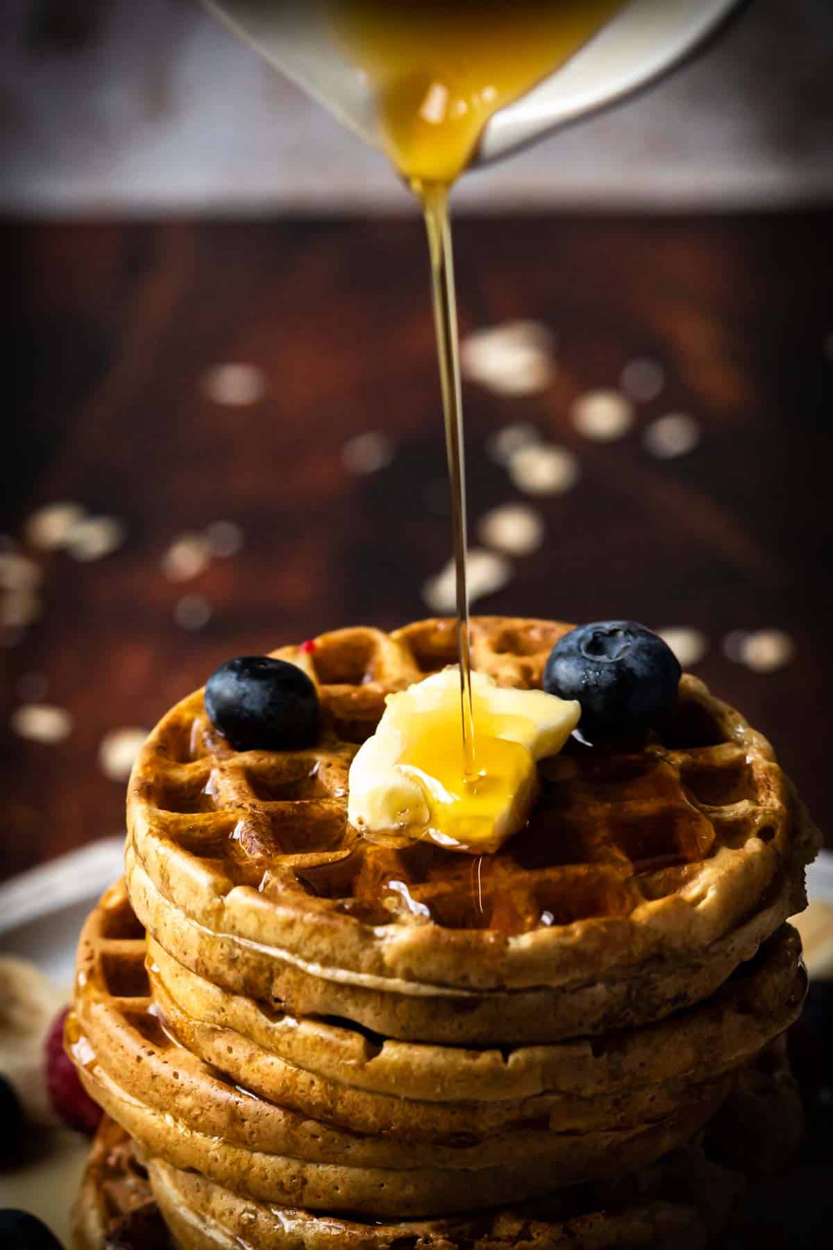 Pouring syrup on a stack of waffles.