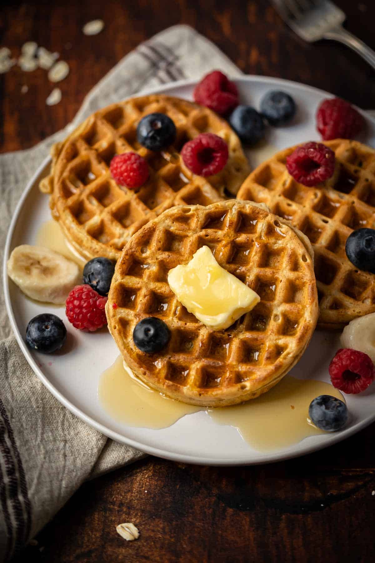 Waffles on a plate with butter and fresh berries.