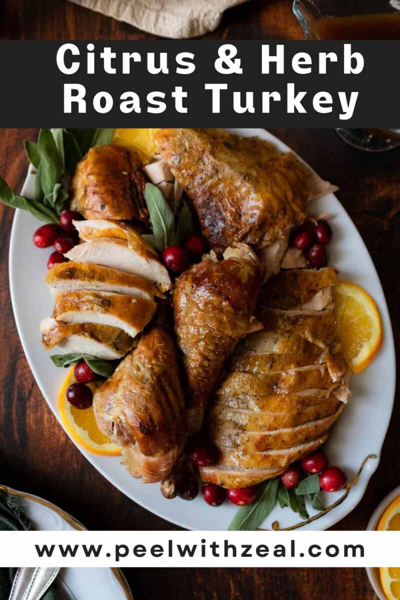 Roasted turkey on a platter with sage leaves and orange slices.