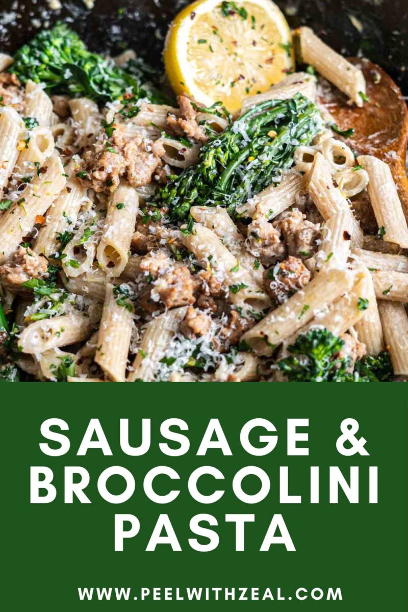 Sausage pasta with broccolini and half a lemon in a pan.