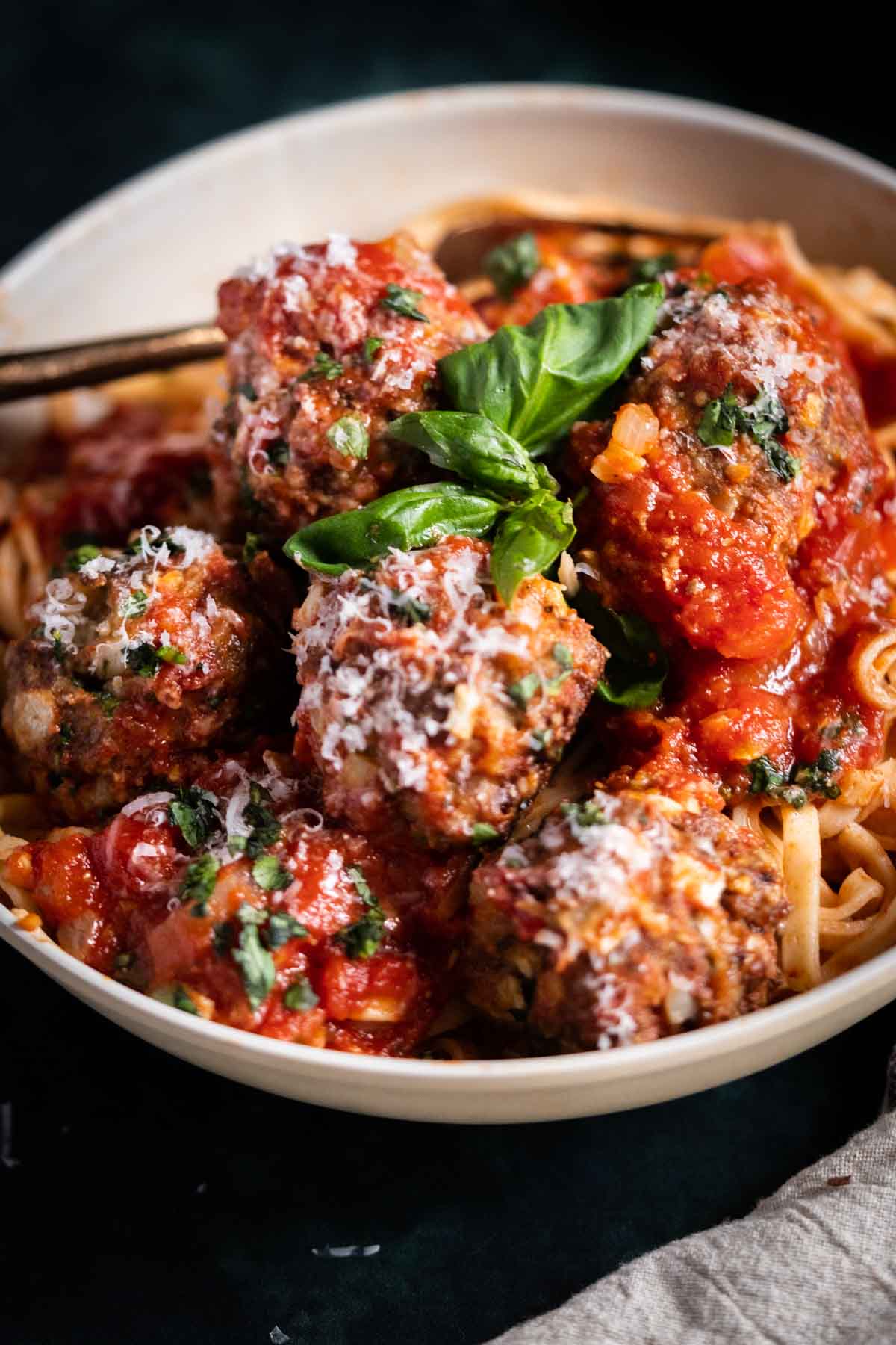 Meatballs in a bowl with tomato sauce and basil.