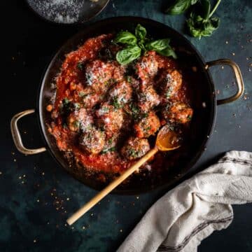 Pan of meatballs in tomato sauce with parmesan cheese.