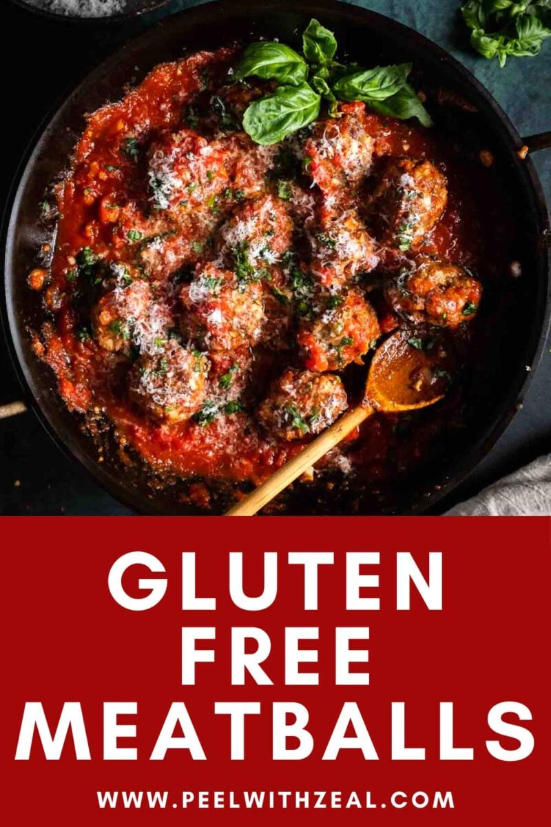 Meatballs in spaghetti sauce in a pan with wooden spoon.