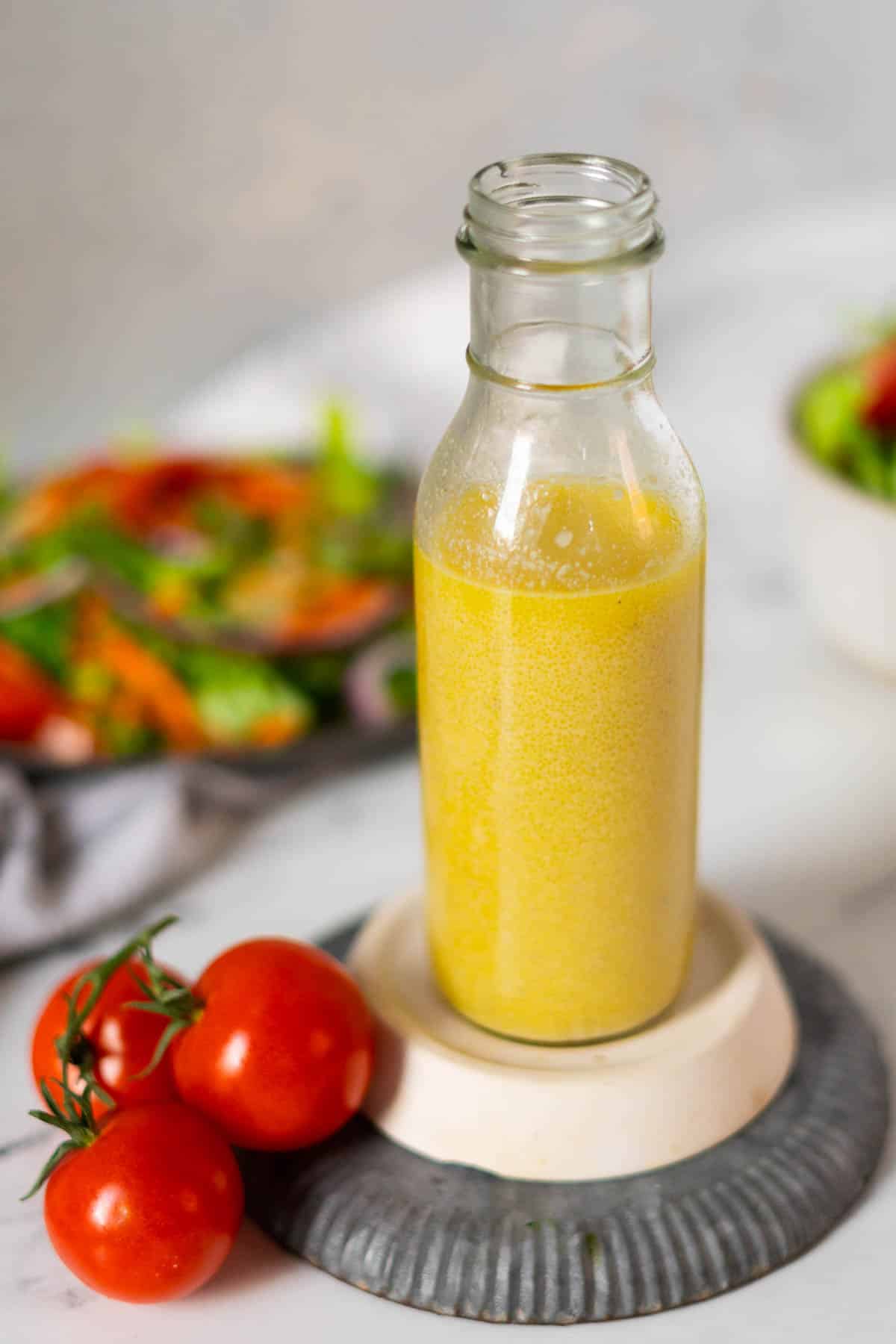 Salad dressing in a bottle with a bunch of red tomatoes.