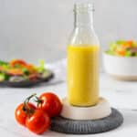 Salad dressing in a bottle with a bunch of red tomatoes.
