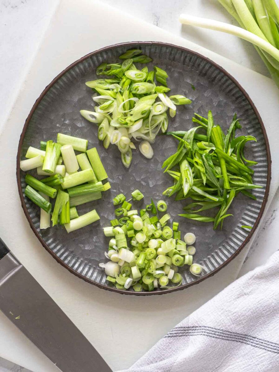 Green onions cut in different ways on a plate.