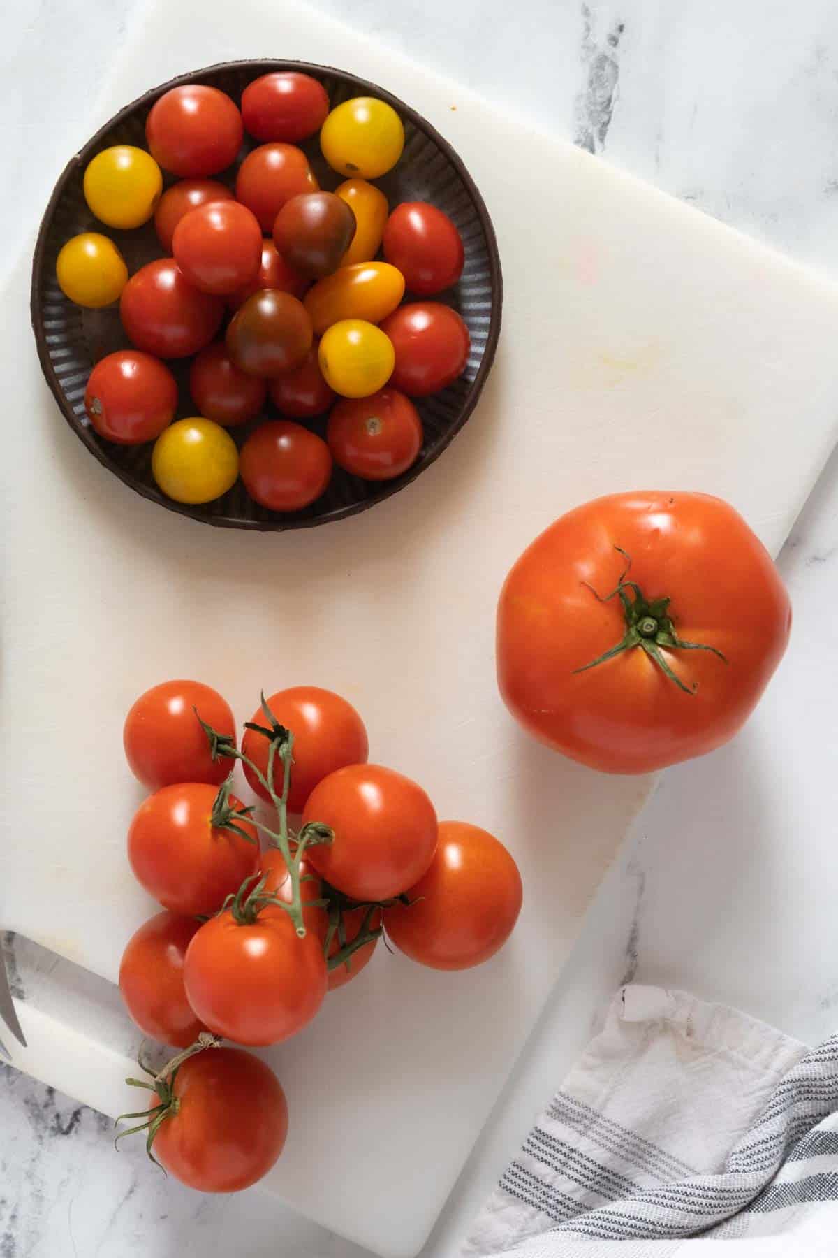 Different types of tomatoes on a cutting board.