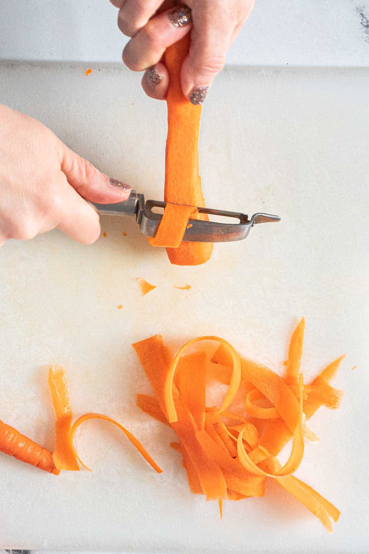 Using a vegetable peeler to make carrot ribbons.