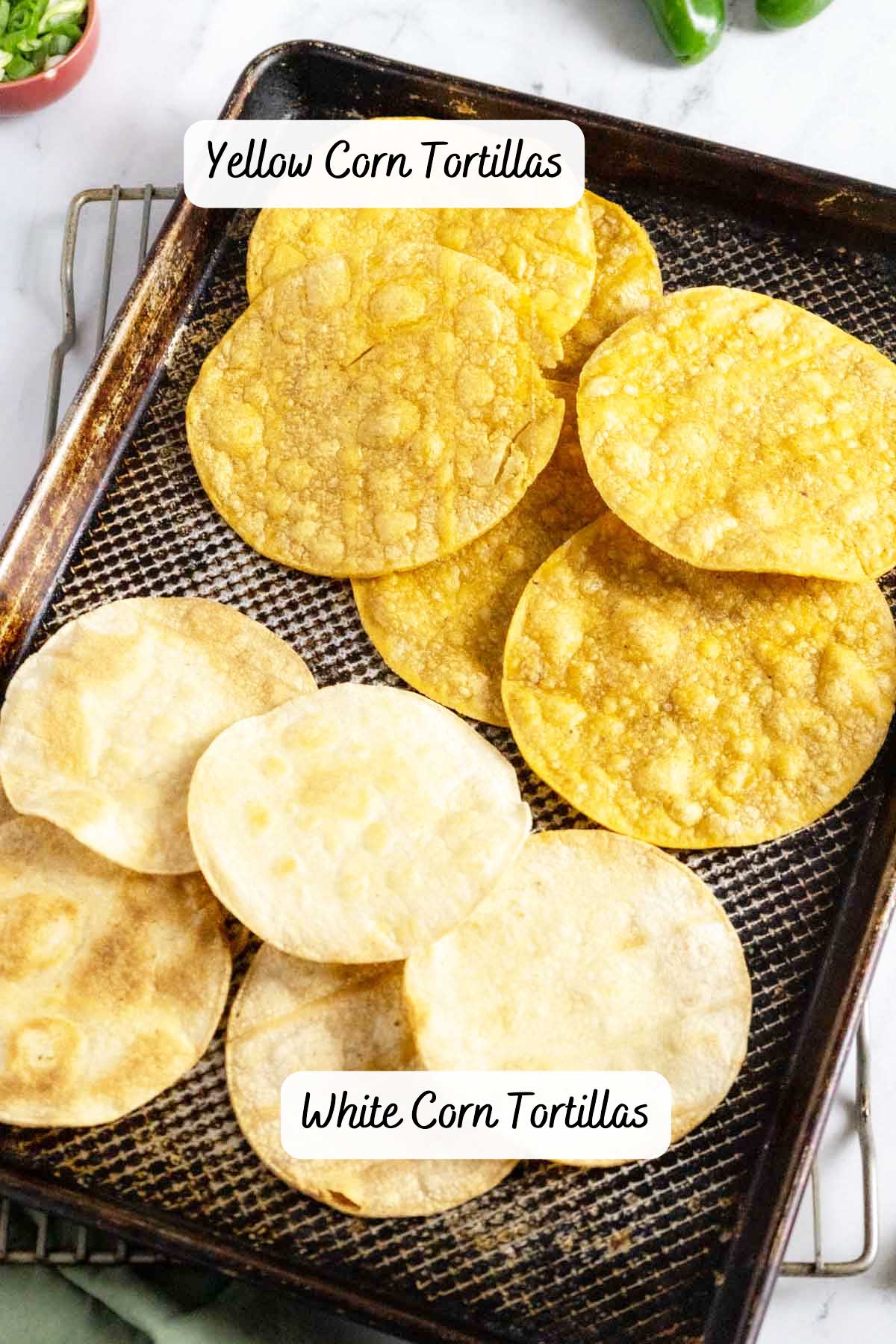 White corn and yellow corn tortillas on a baking sheet.