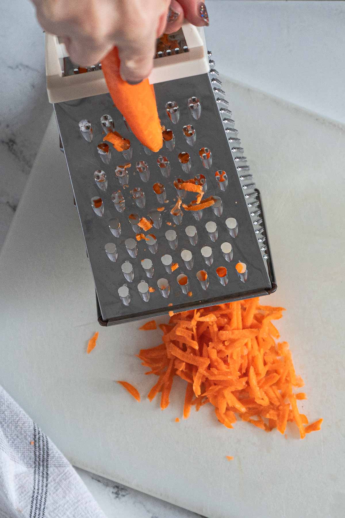 Using a box grater to shred a carrot.