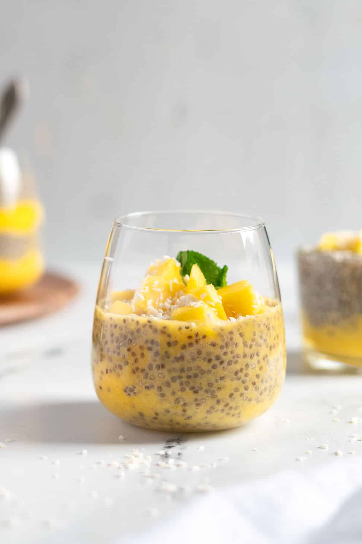 Mango chia pudding in a glass with coconut flakes.