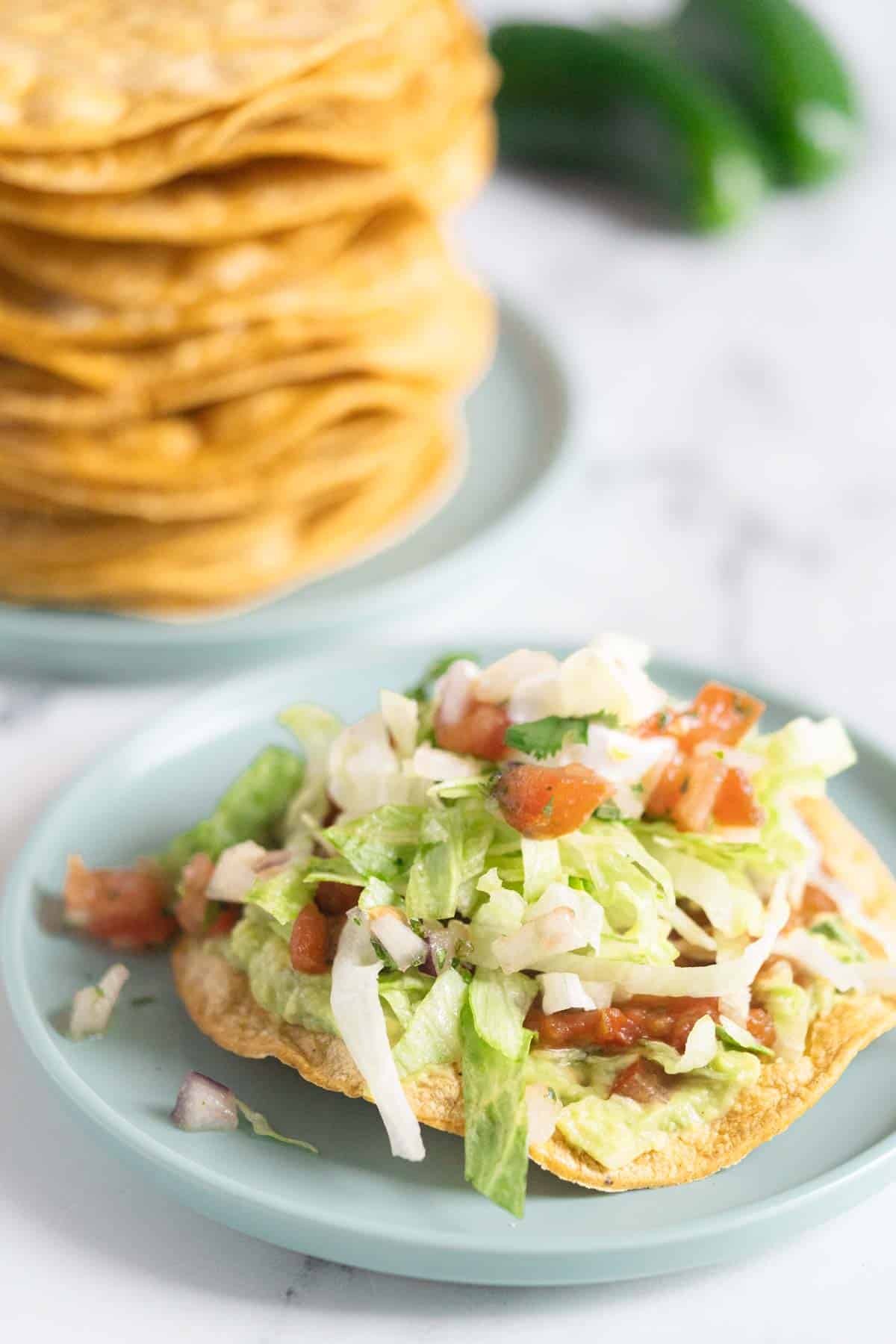 Tostada topped with refried beans, guacamole and lettuce.