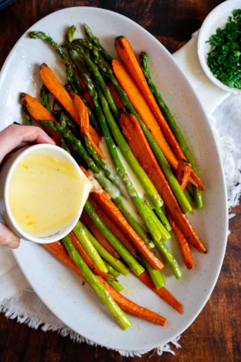 Pouring lemon dressing on roasted vegetables.