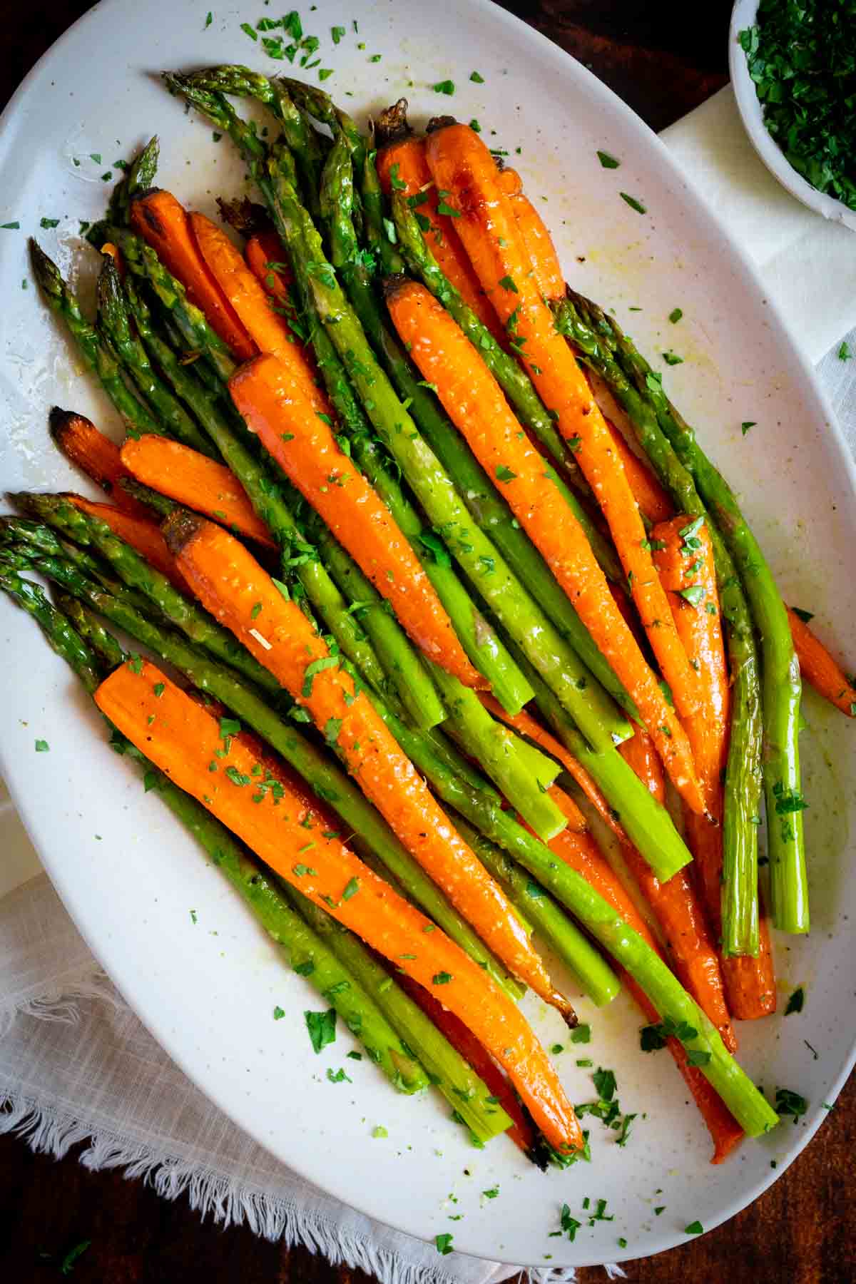 Cooked asparagus and carrots on a plate with fresh herbs.