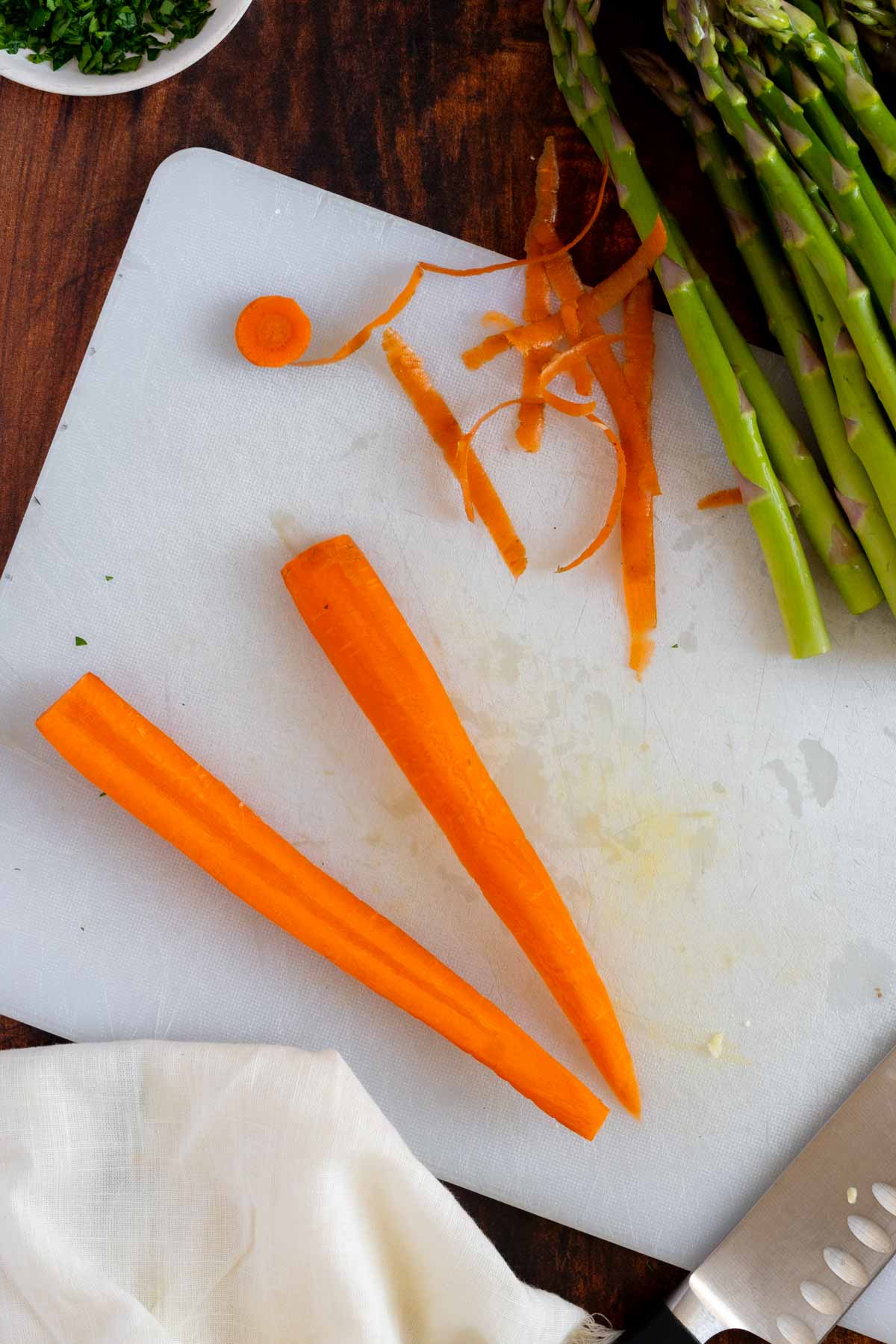 Cutting a carrot on a white cutting board.