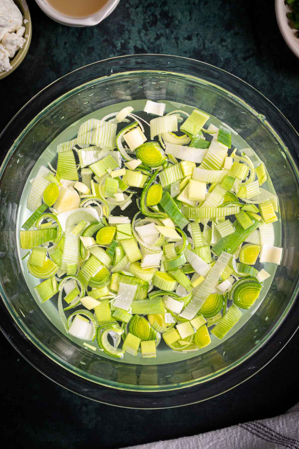 Sliced leeks in a bowl with water.