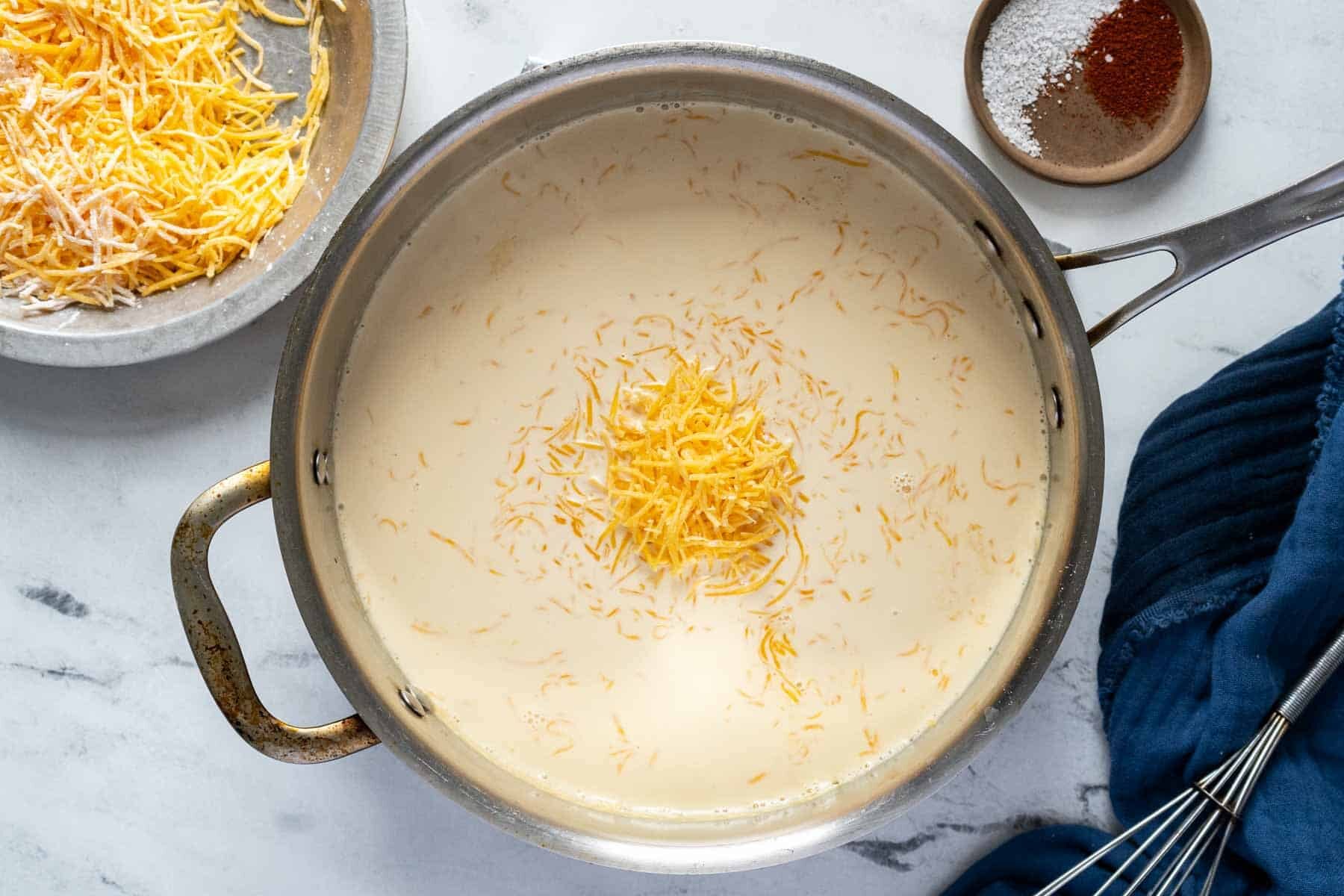 Making cheese sauce in a pan with cheddar cheese.
