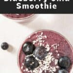 Two smoothies in a glass with blueberries and coconut.