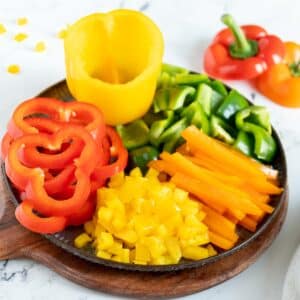 Colorful bell peppers cut different ways on a plate.