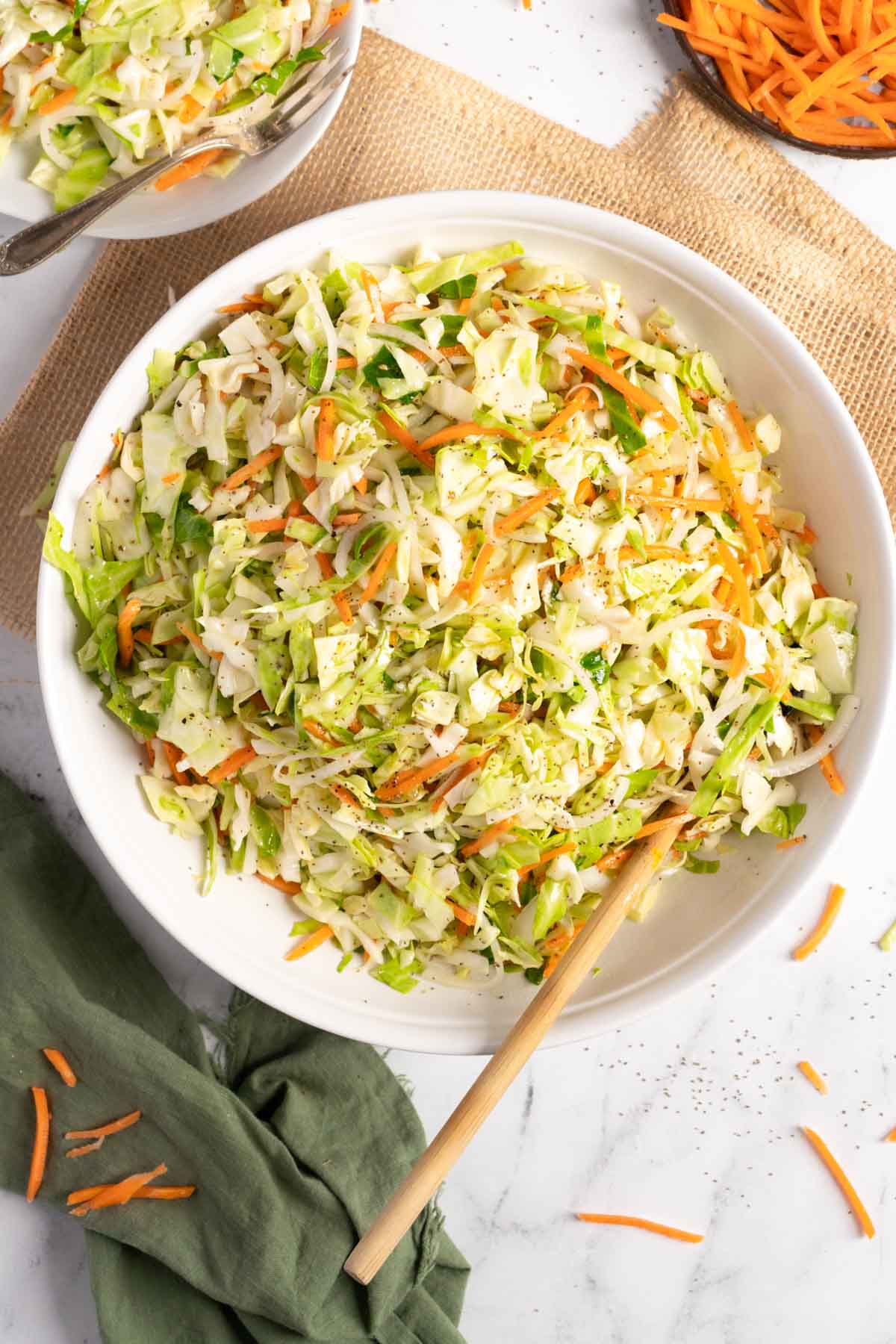 Coleslaw in a serving bowl with a wooden spoon.