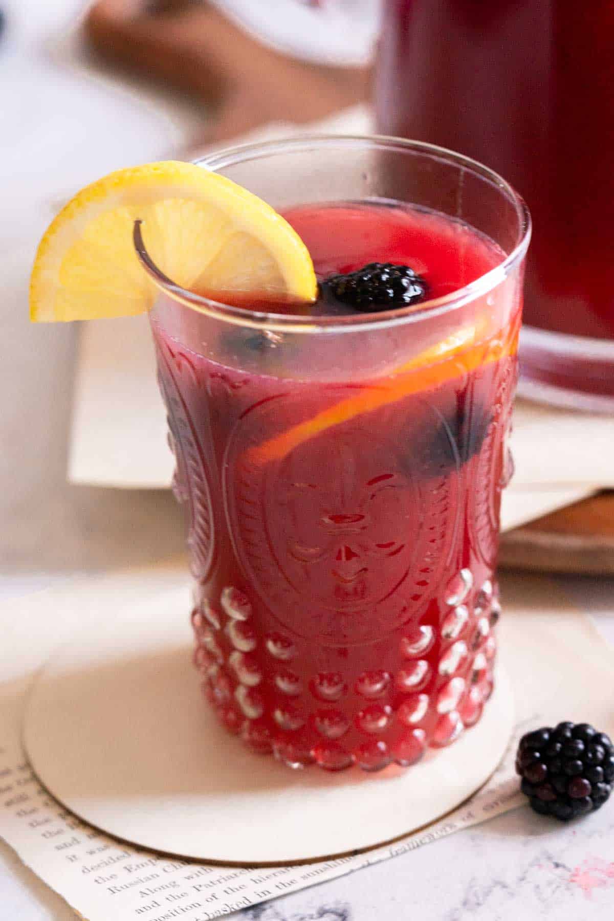 Glass of lemonade with lemon slices and blackberries.