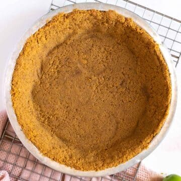 Graham cracker pie crust in a pan on a cooling rack.