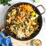 Pad thai in a pan with a wooden spoon.