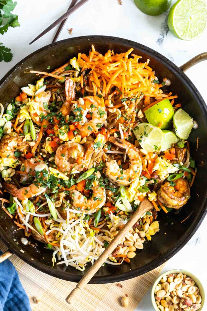 Pad thai in a pan with a wooden spoon.