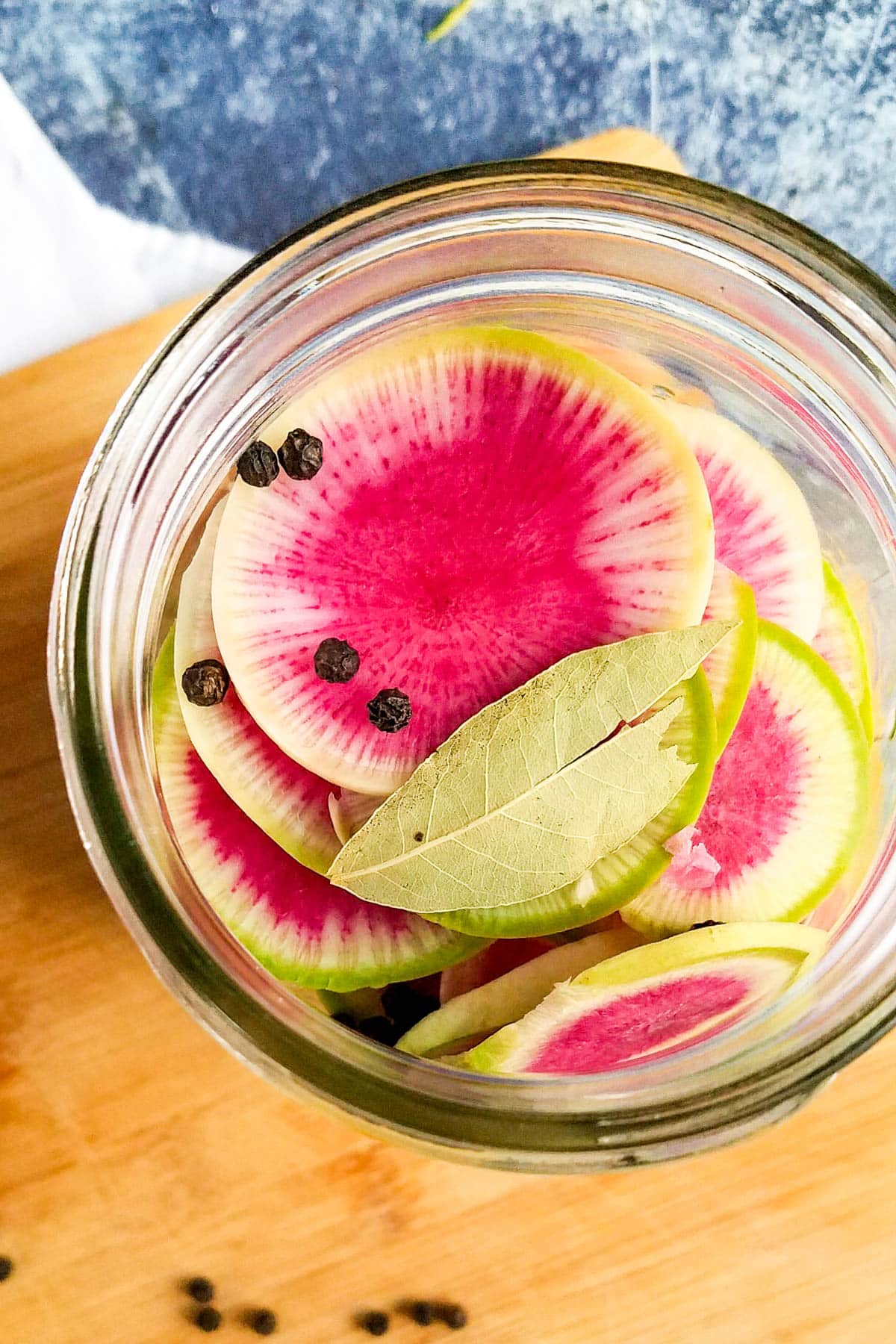 Radishes in a jar with peppercorns and bay leaf.