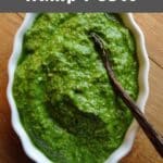 Pesto in a bowl with a wooden spoon.